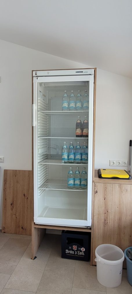 Kühlschrank Kühlschrank mit gläserner Tür, leer bis auf einige Flaschen auf den Regalen.