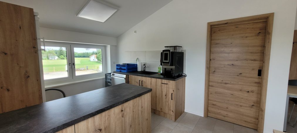 Küche Küche mit Holzmöbeln, Fenster und Zugang zu einem Raum mit einer Tür.