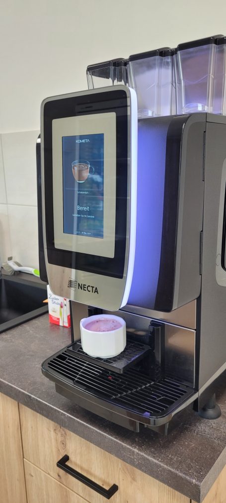 Kaffemaschine Kaffeebereiter mit digitalem Display und darunter einer Tasse auf der Ablage.